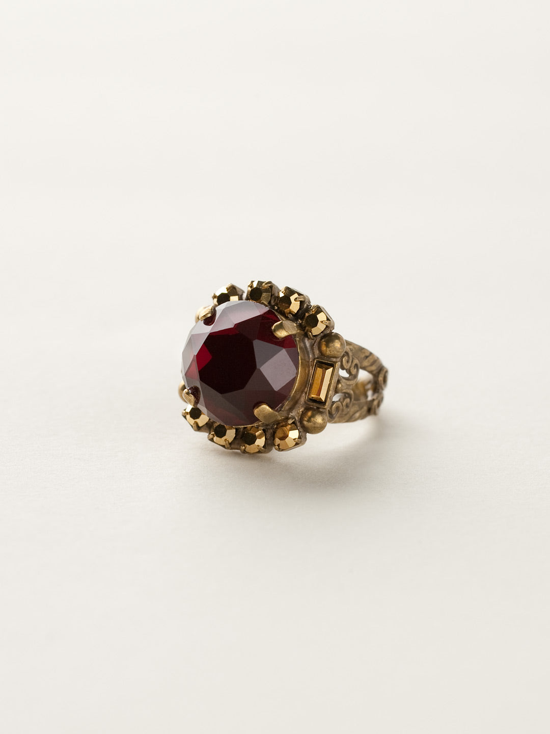 Round Crystal Encrusted Cocktail Ring - RCQ43AGGGA - <p>A large round gemstone surrounded by petite round crystals works as the focal point of this cocktail ring. Which is further accented by an ornate decorative band. Ring size: 7 (US) From Sorrelli's Go Garnet collection in our Antique Gold-tone finish.</p>