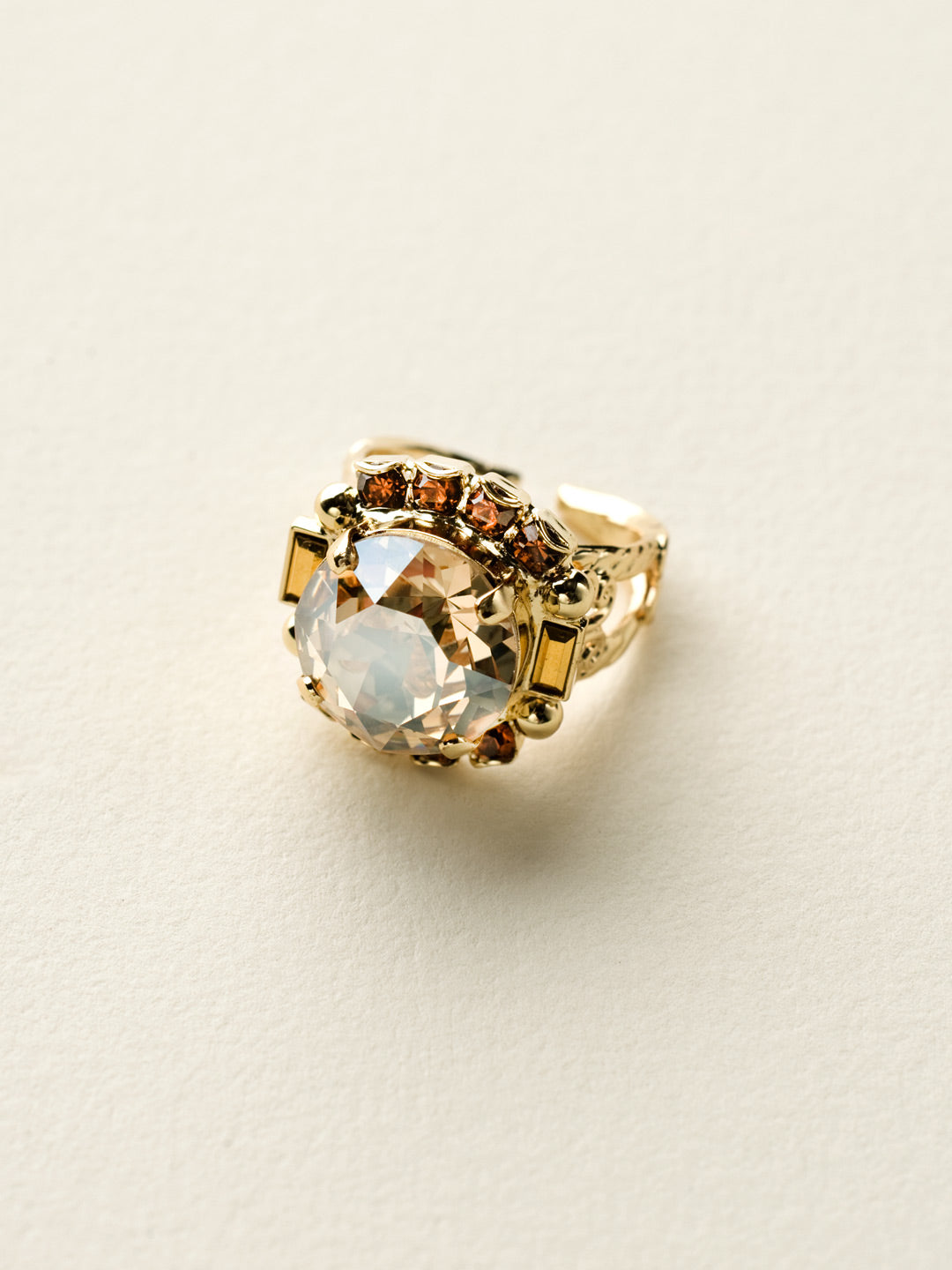 Round Crystal Encrusted Cocktail Ring - RCQ43BGGOL - <p>A large round gemstone surrounded by petite round crystals works as the focal point of this cocktail ring. Which is further accented by an ornate decorative band. Ring size: 7 (US) From Sorrelli's Gold Leaf collection in our Bright Gold-tone finish.</p>